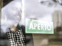Business owner turning as open (aberto in portuguese) for business sign in their storefront window